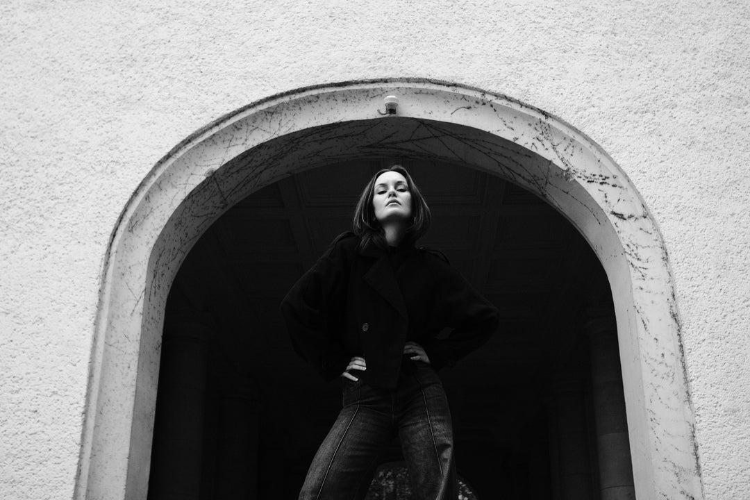 Helena Wedekind standing in a stone archway, hands on hips