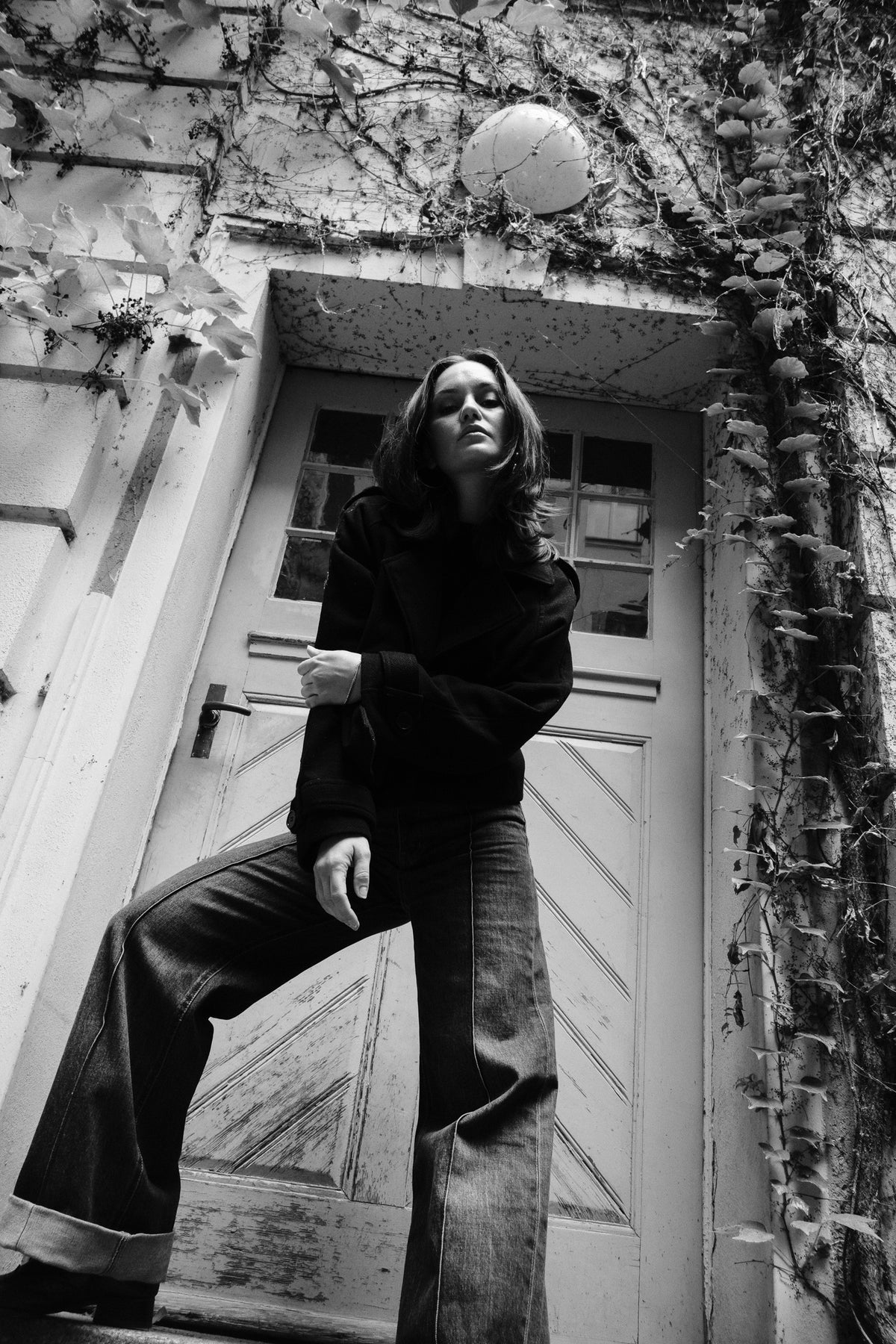 Helena Wedekind on the steps of an ivy-covered doorway, one foot raised