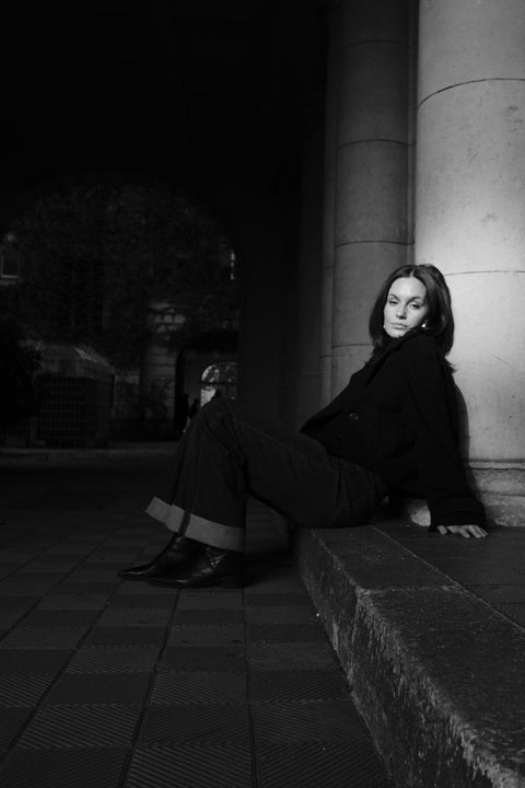 Helena Wedekind sitting on a stone ledge between columns, looking over her shoulder