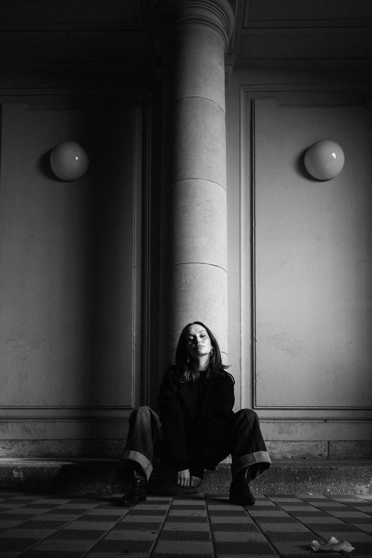 Helena Wedekind crouched against a column between two globe lamps, eyes closed