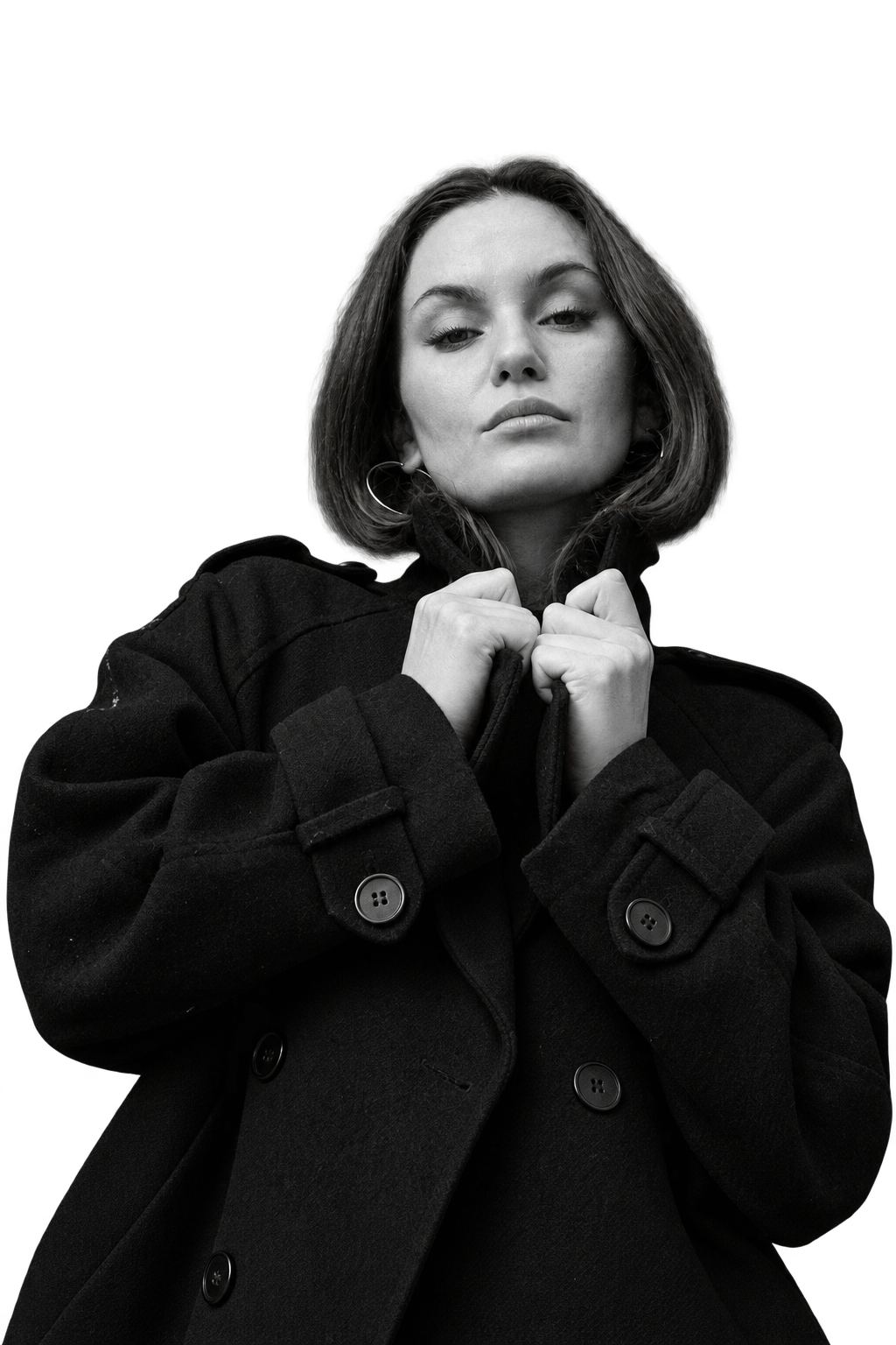 Helena Wedekind holding the collar of her black coat, looking down at the camera