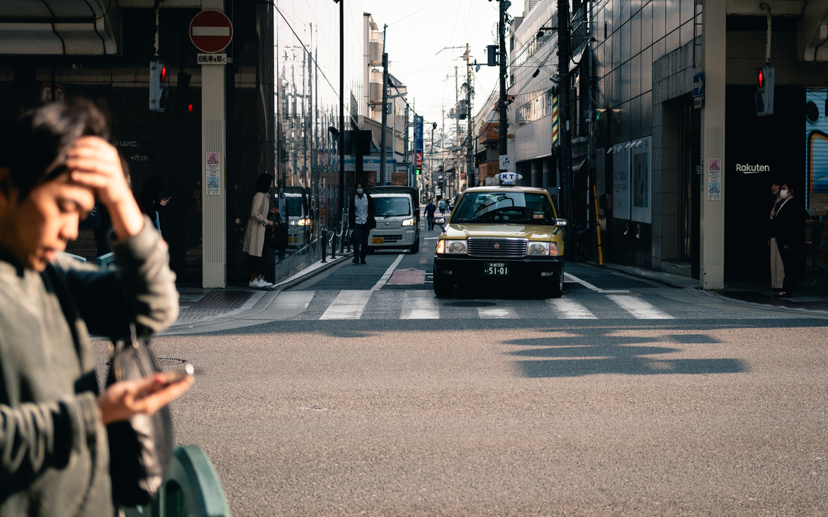 Man checking his phone, a yellow taxi behind him