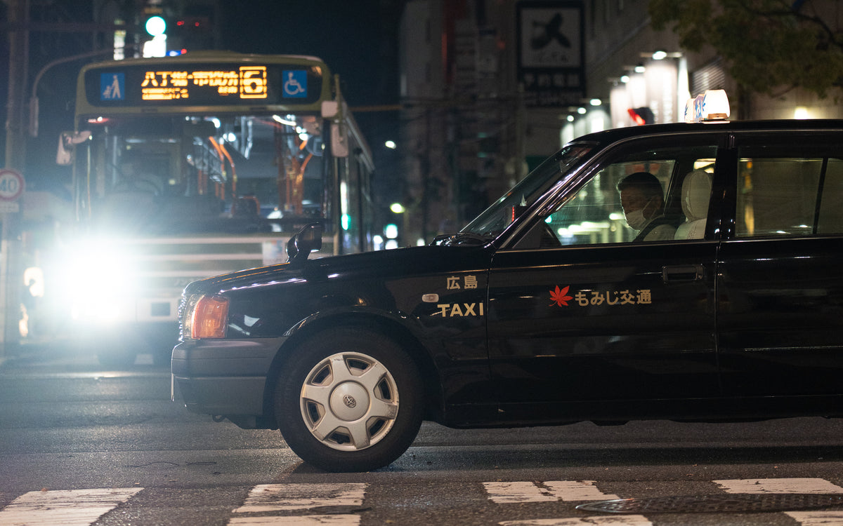 Black taxi passing a lit bus at night