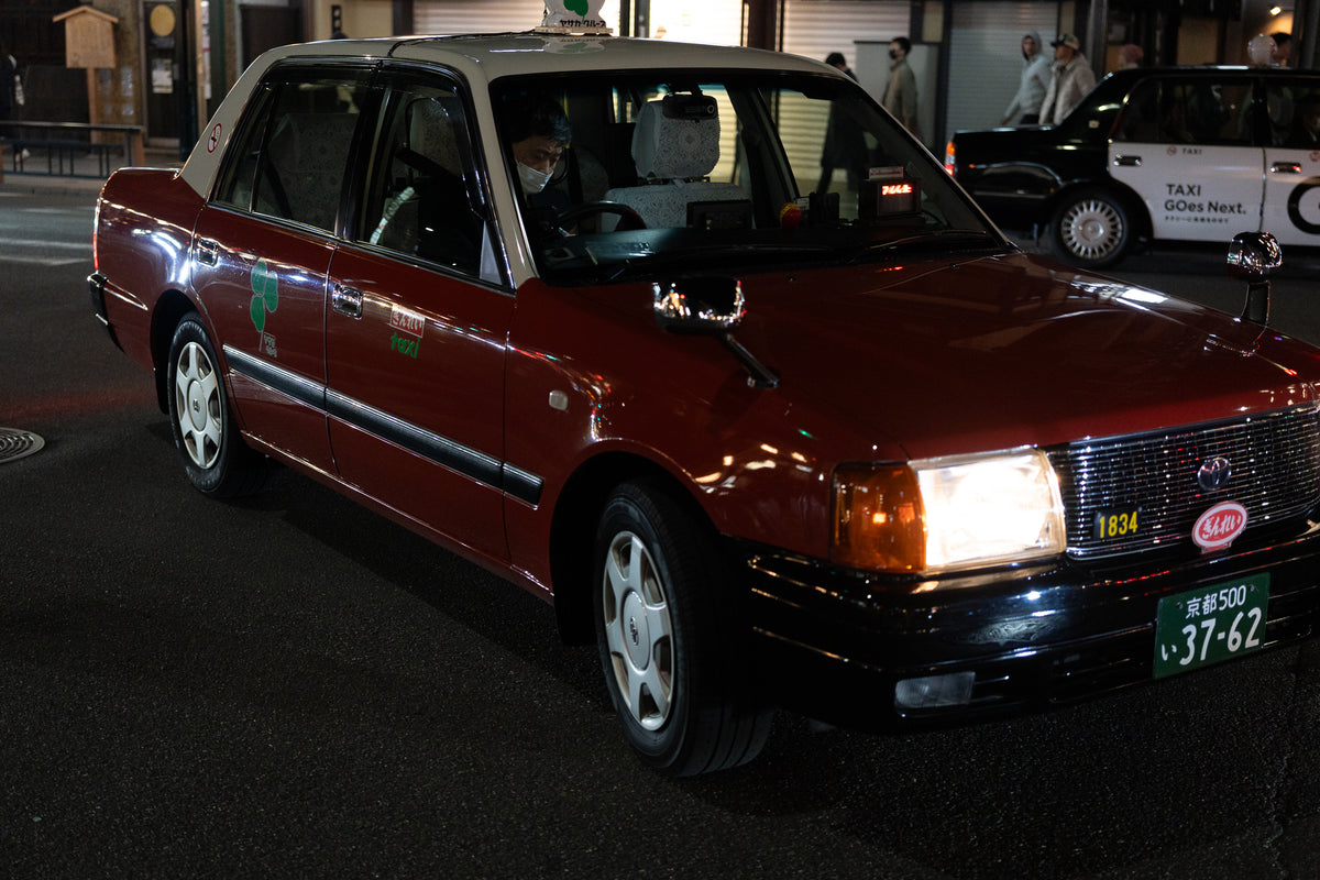 Red and cream taxi with its headlights on