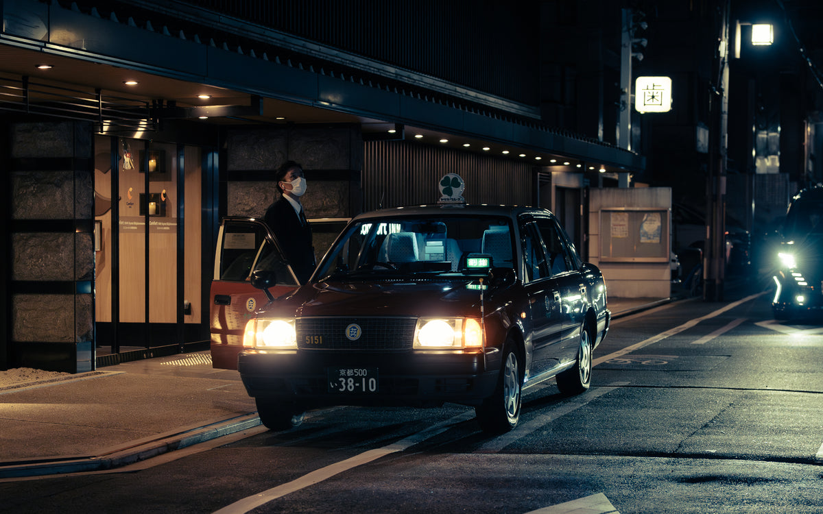 Taxi waiting at a door, the driver standing beside it